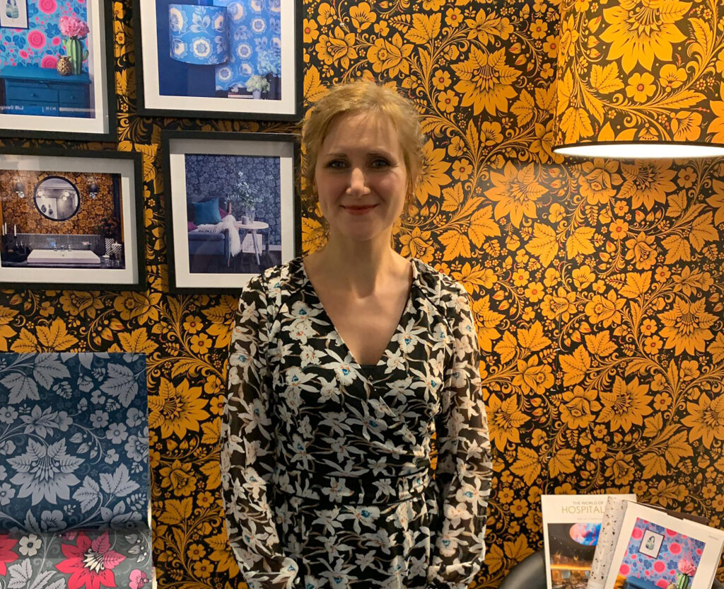 Olga Shevchenko from Olenka Design in front of some of her Khokhloma-inspired wallpaper designs.