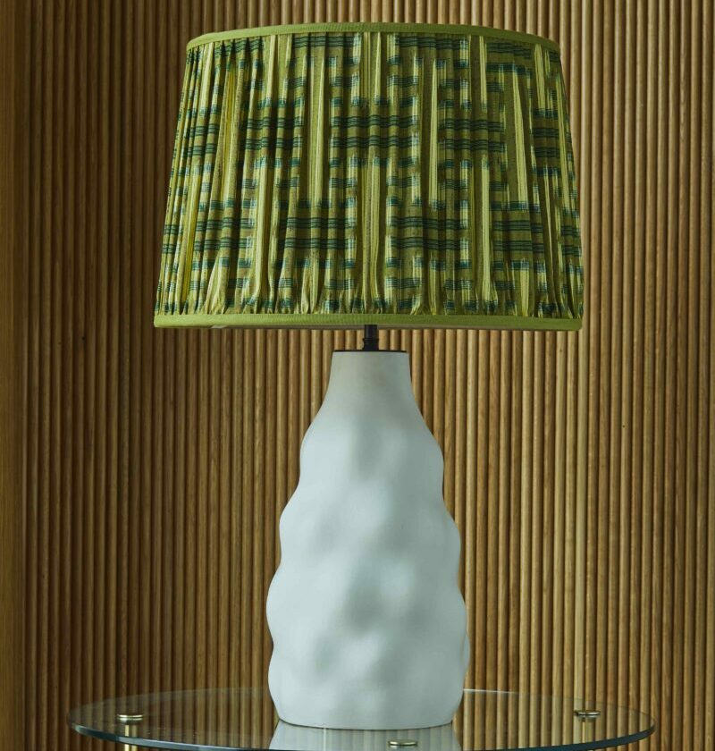 An elegant handmade white pottery lamp base topped with an eclectic green lampshade from Samarkand Design.