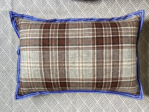 A brown wool check cushion with blue stripe trim.