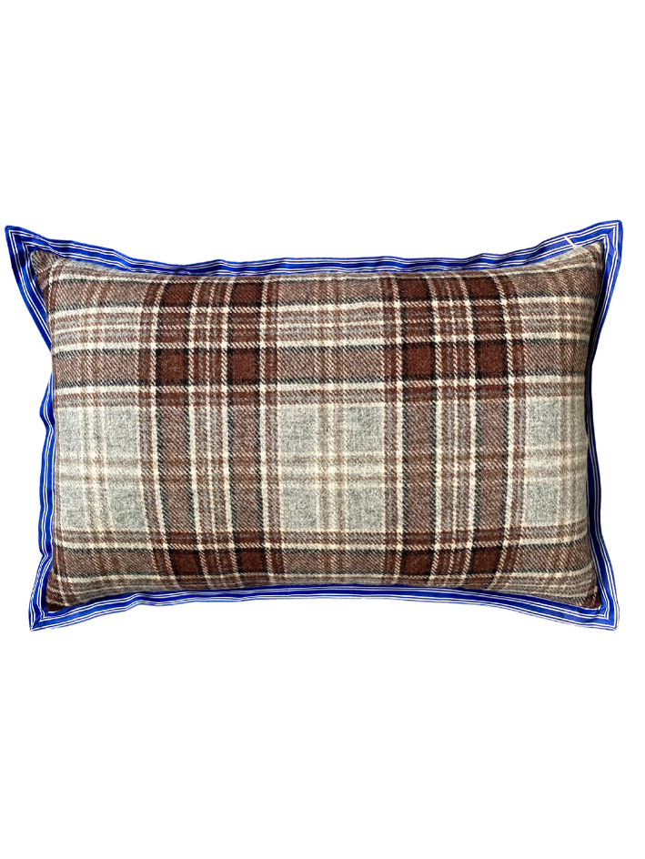 The brown woollen check reverse of a floral linen cushion with blue striped trim.