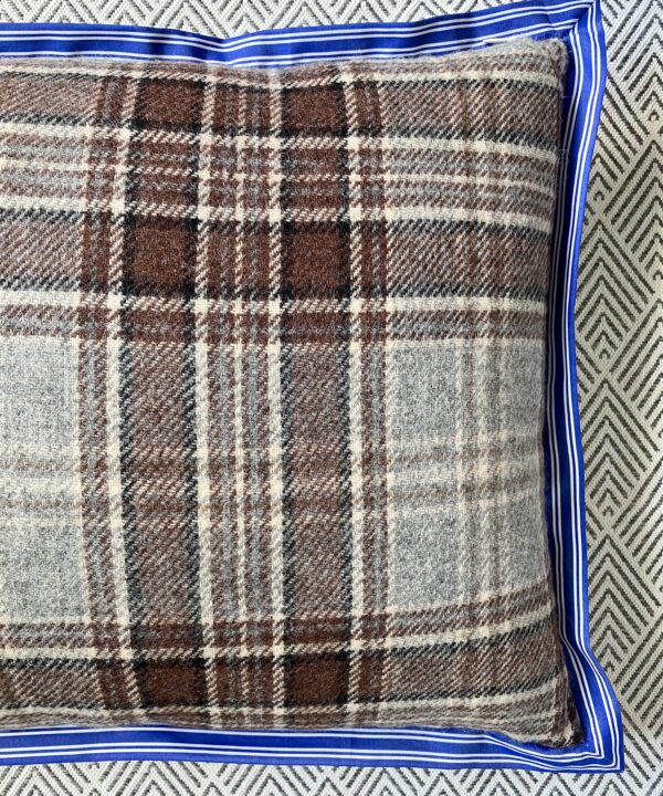 Detail of a brown plaid cushion with a striped blue trim.