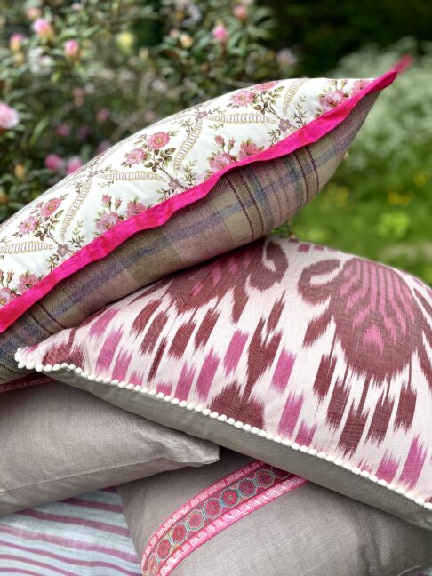 A pile of pink floral and Ikat cushions.