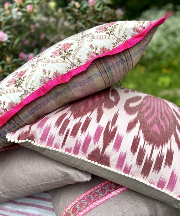 A pile of pink floral and Ikat cushions.