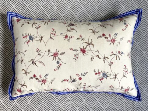 Floral sprig cushion in linen with blue striped trim.