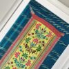 Framed embroidery art showcasing a vintage, embroidered Thai panel in yellow on a turquoise silk mount.