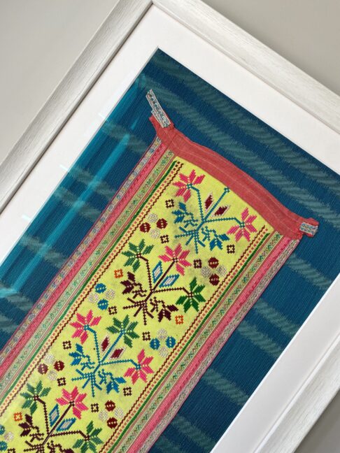 Framed embroidery art showcasing a vintage, embroidered Thai panel in yellow on a turquoise silk mount.