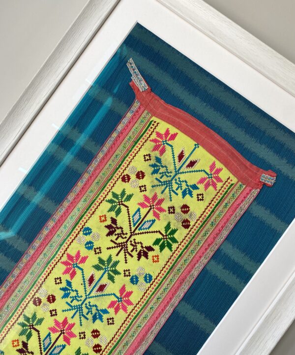 Framed embroidery art showcasing a vintage, embroidered Thai panel in yellow on a turquoise silk mount.