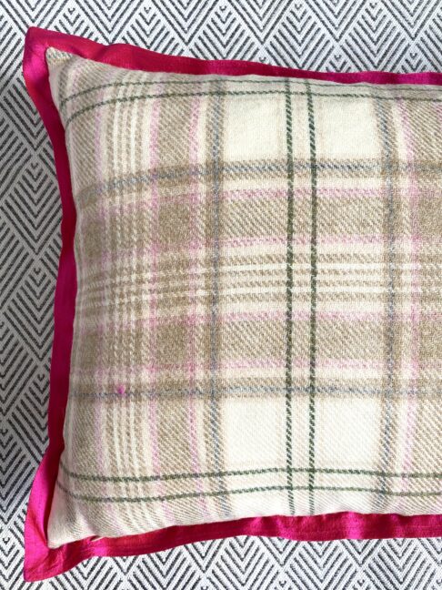 Detail of a pale pink, green and beige plaid cushion reverse with a hot pink silk trim.