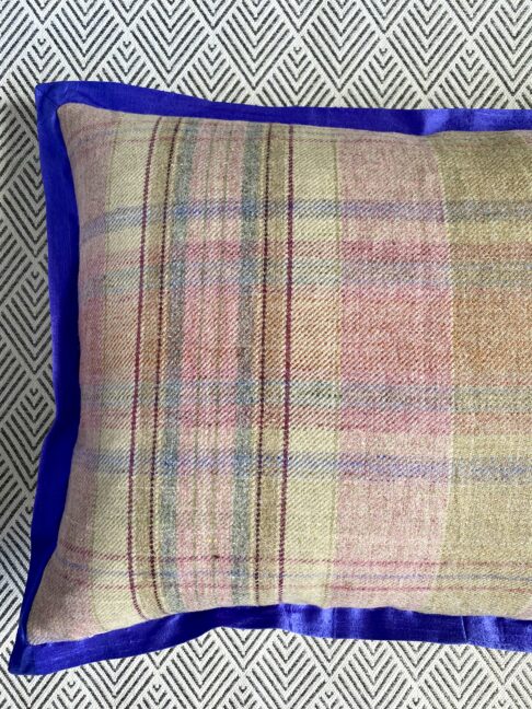 Detail of a tartan cushion reverse with a royal blue silk trim.