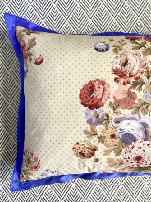 Detail of a vintage floral chintz cushion with a blue silk trim.