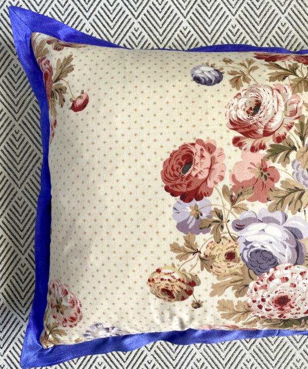 Detail of a vintage floral chintz cushion with a blue silk trim.