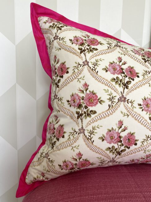 A pink silk trimmed vintage floral cushion with a French style rose trellis design.