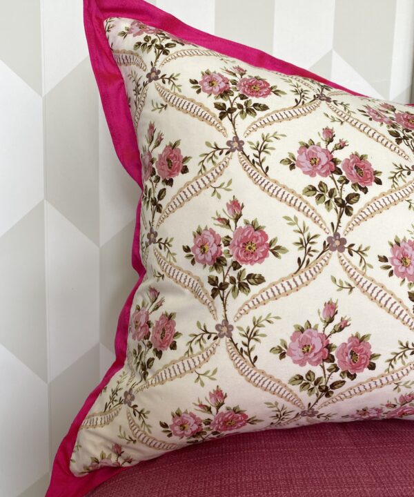 A pink silk trimmed vintage floral cushion with a French style rose trellis design.