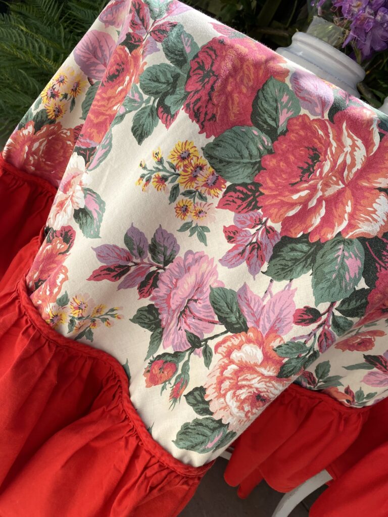 A vintage floral tablecloth with a bold, red frill.