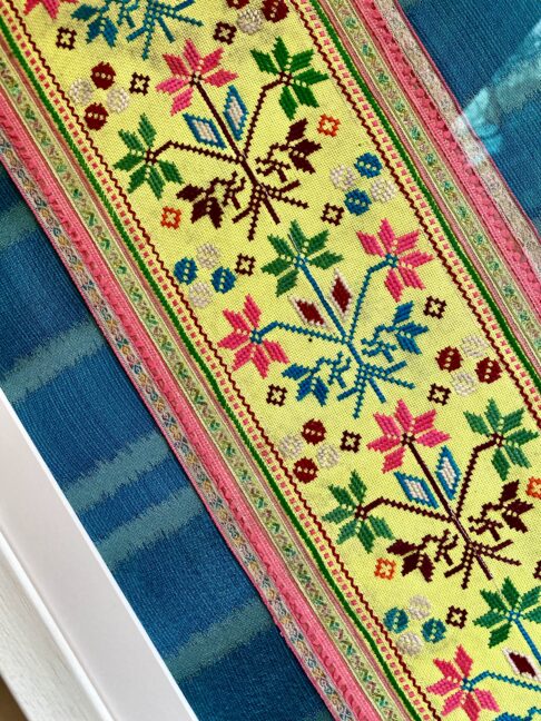 Handmade embroidery panel from Thailand framed against teal blue silk.