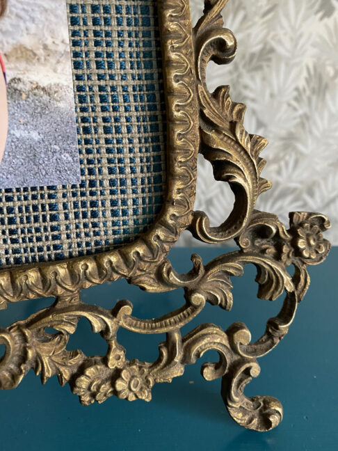 Detail of an ornate, scrolling, brass photo frame from Spain.