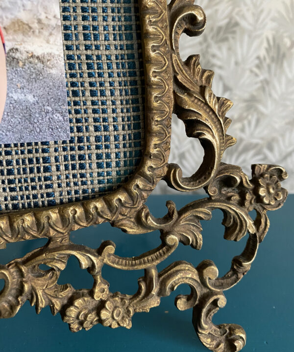 Detail of an ornate, scrolling, brass photo frame from Spain.