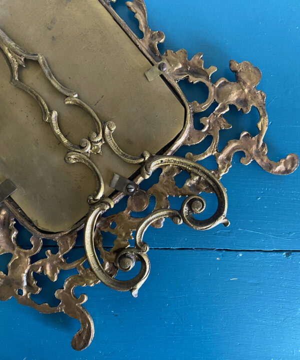 The back of a vintage, brass, photo frame.