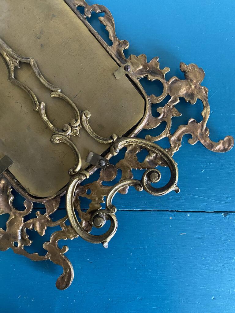 The back of a vintage, brass, photo frame.