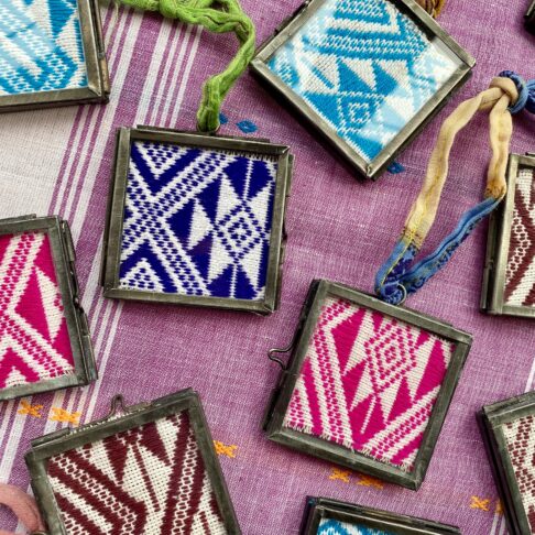 Detail of framed Thai textiles displayed in miniature glass and metal frames.