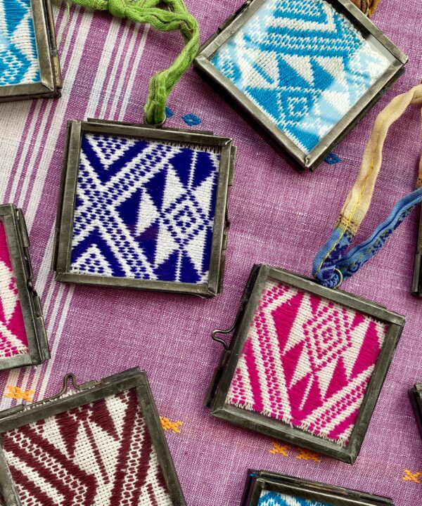 Detail of framed Thai textiles displayed in miniature glass and metal frames.