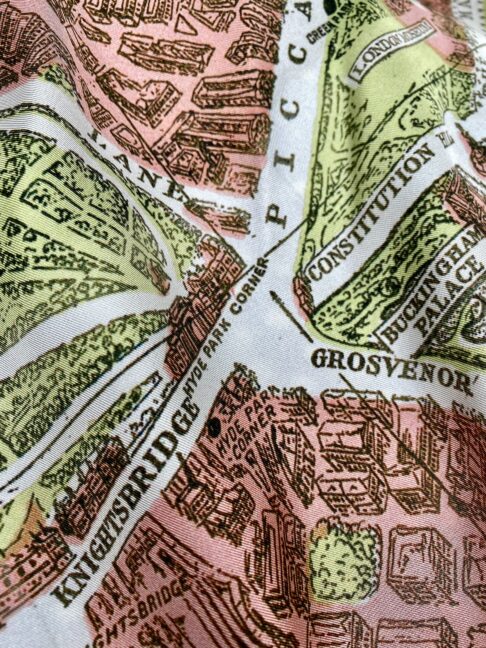 A salmon pink and pale green silk scarf depicting the city streets of London, England.