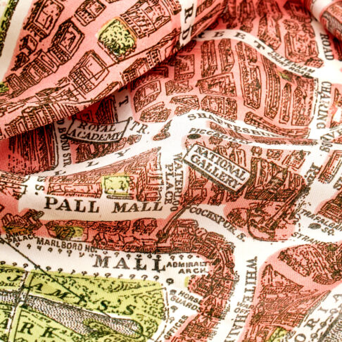 A detail of a pink silk scarf depicting a printed vintage map of London's streets.