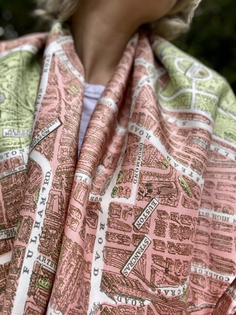 A model's shoulders are draped with this elegant pink silk scarf showcasing a vintage map of the London streets.