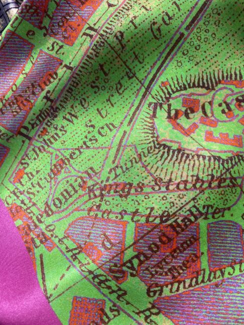 A magenta pink and lime green silk scarf printed with a vintage map of Edinburgh.