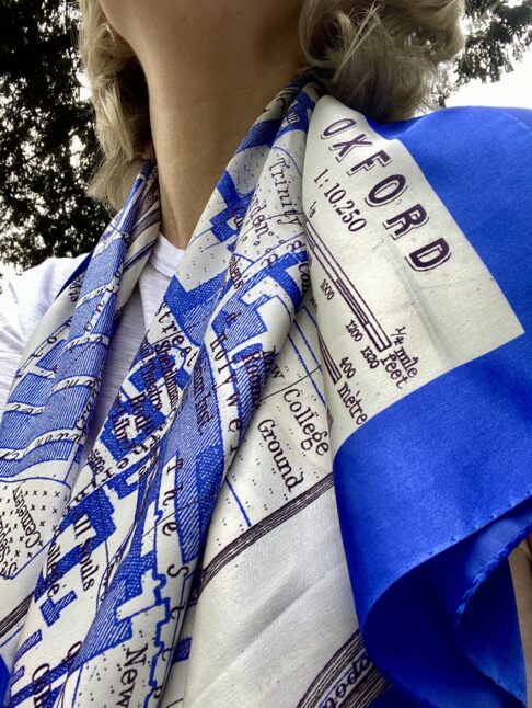 A deep blue silk scarf depicting the city of Oxford, draped on the shoulders of a model.