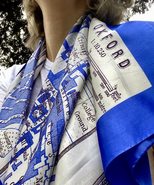 A deep blue silk scarf depicting the city of Oxford, draped on the shoulders of a model.