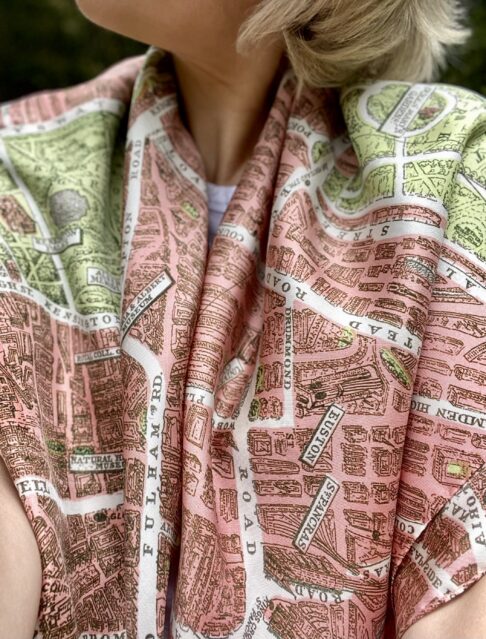 A model wearing a luxury pink silk scarf printed with the city streets of London taken from a vintage map.