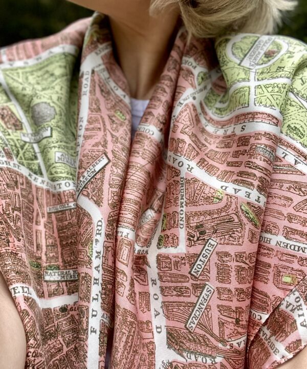 A model wearing a luxury pink silk scarf printed with the city streets of London taken from a vintage map.