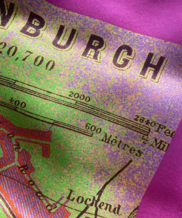 Detail of a magenta pink and lime green silk scarf depicting the city of Edinburgh.