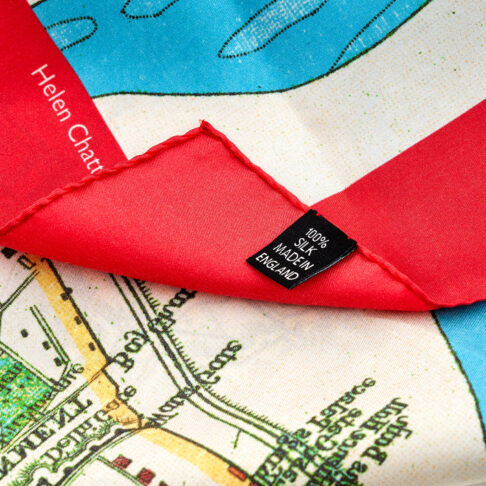 A detail shot showing the silk label on a red, blue and green silk map print scarf depicting Delhi, India.