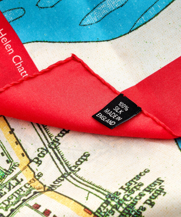 A detail shot showing the silk label on a red, blue and green silk map print scarf depicting Delhi, India.
