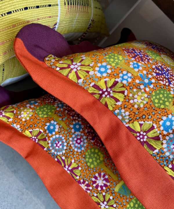 Detail of a pair of scalloped edge cushion with a colourful Aboriginal print.