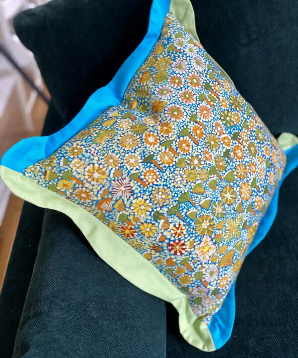 Turquoise, green and yellow cushion in a cheerful Aboriginal art botanical print pattern.