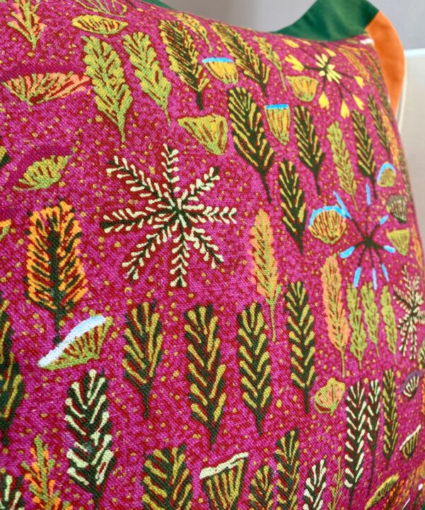 Detail of a botanical theme Aboriginal art print across a deep pink cushion.