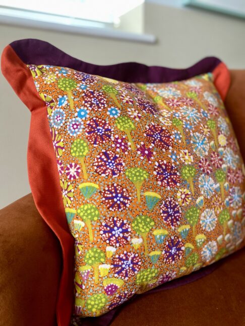 A brightly-coloured floral linen cushion in a pattern taken from an original indigenous Aboriginal art print.