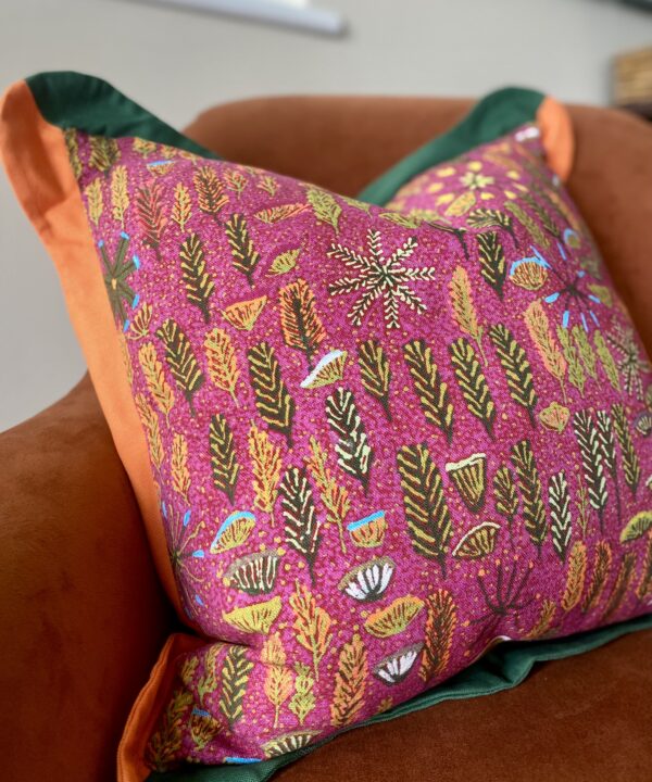 Pink indigenous Aboriginal art print on linen cushion with a scalloped green and orange Oxford trim.