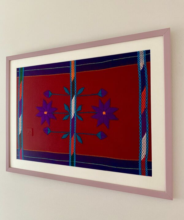 A handmade embroidery art textile in deep red and purple with a pale mauve frame and shown shot from an angle.