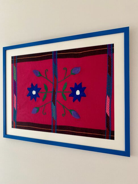 Blue framed embroidery art Mexican handmade textile shot from an angle.