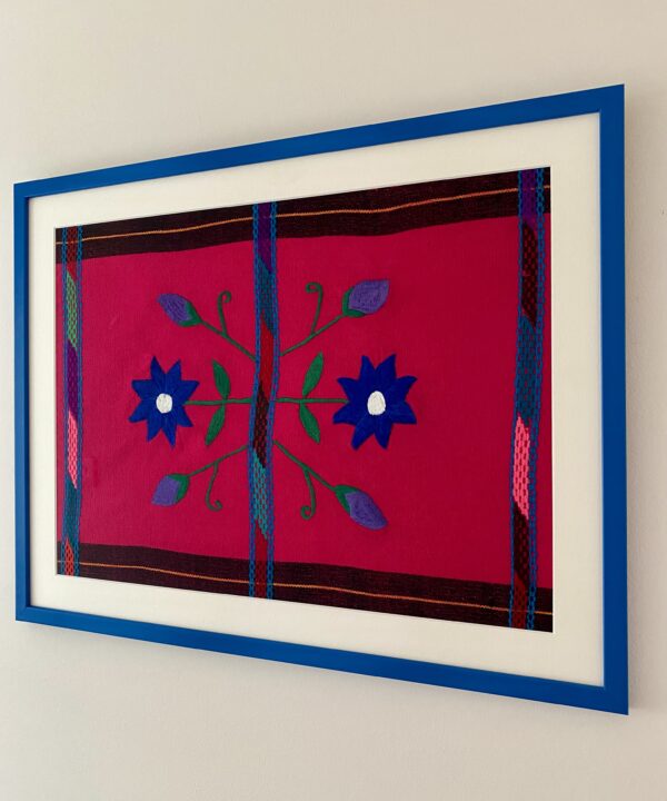 Blue framed embroidery art Mexican handmade textile shot from an angle.