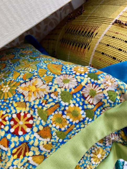 Detail of a pair of lime and blue Aboriginal art print cushions with scalloped Oxford edges, from our eclectic, cushions and throws edit.