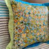 A multi-coloured cushion depicting Australian outback flora sat on a striped sofa.