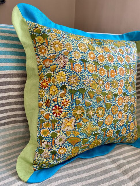 A multi-coloured cushion depicting Australian outback flora sat on a striped sofa.