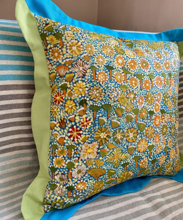 A multi-coloured cushion depicting Australian outback flora sat on a striped sofa.