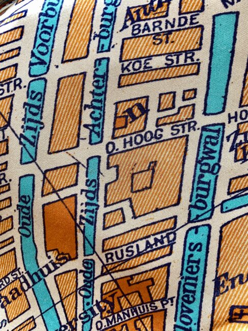 Detail of an orange silk scarf with turquoise accents depicting a vintage map of Amsterdam.