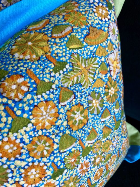 Aboriginal art design on a cheerful turquoise blue, Spring green and yellow floral cushion.